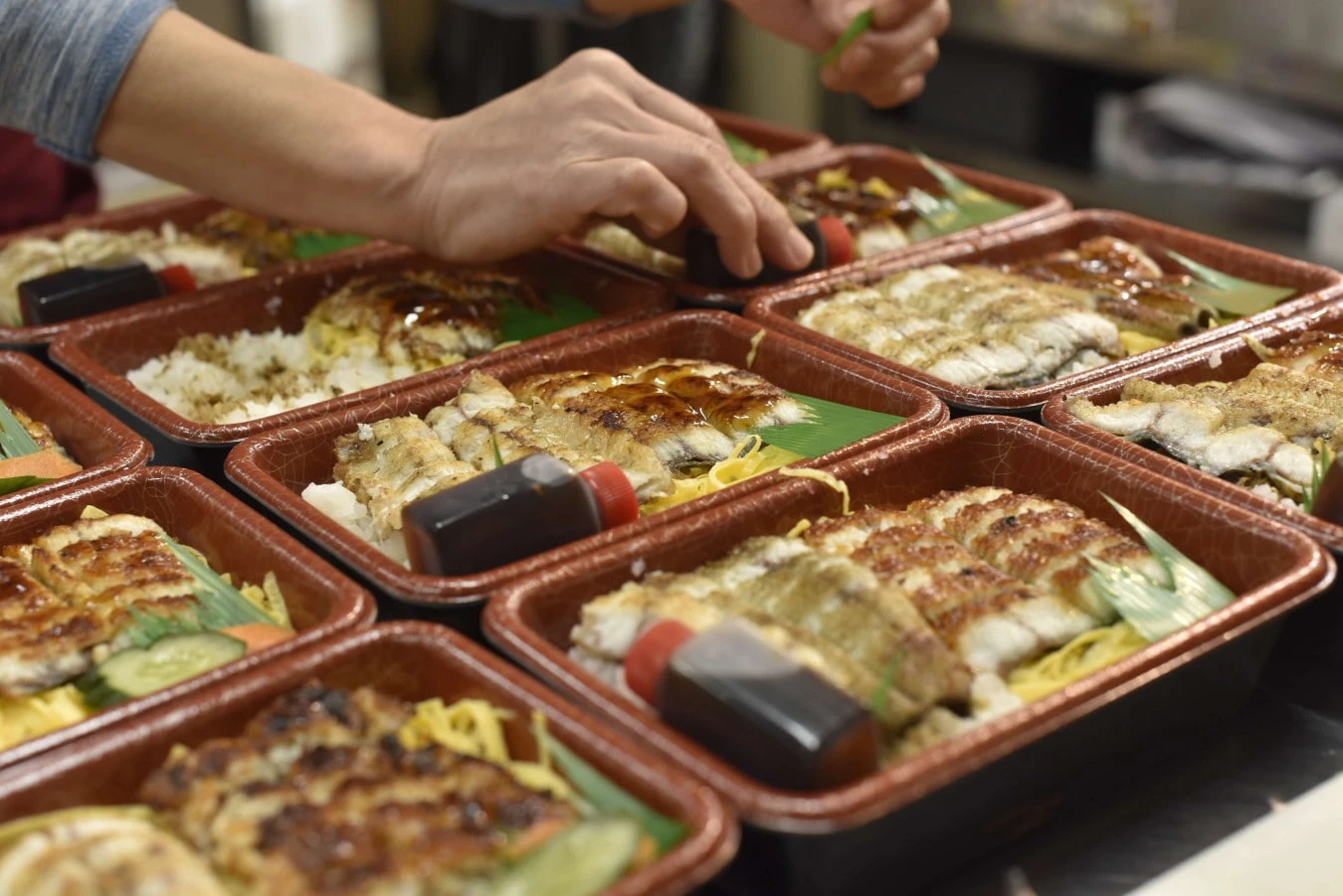 たくさんのうな丼弁当を詰めるようす
